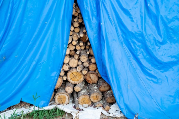 Pilha de lenha empilhada em uma fazenda para passar o inverno frio é coberta por plástico para evitar