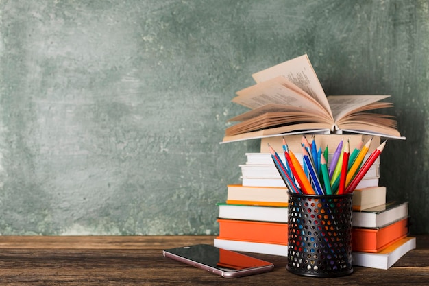 Pilha de livros e artigos de papelaria no fundo do conselho escolar