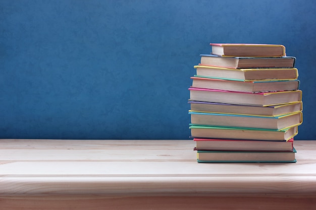 Pilha de livros em capas de cor em uma mesa de madeira.