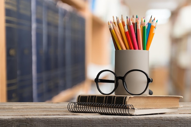 Pilha de livros, óculos e lápis coloridos na mesa