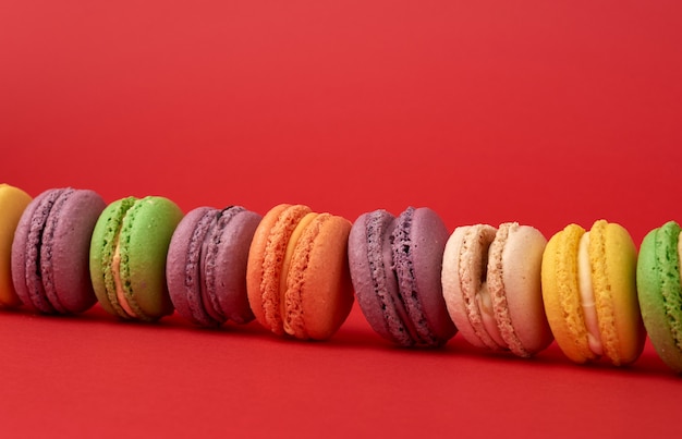 Pilha de macarons assados multi-coloridas em uma superfície vermelha