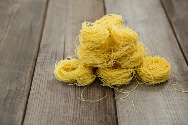 Pilha de massa de capellini em superfície de madeira