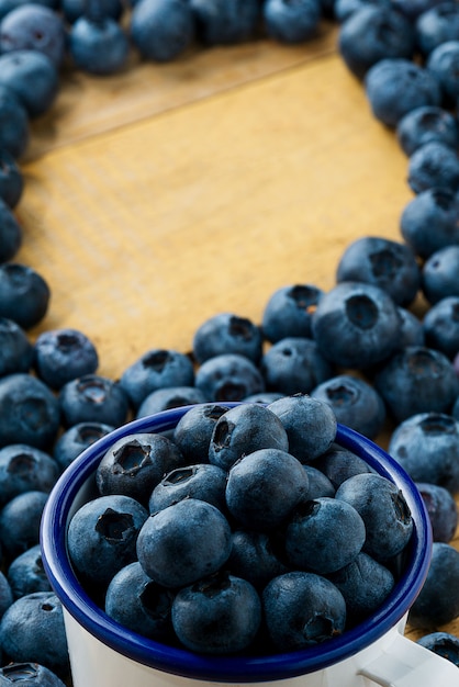 Pilha de mirtilos no copo e na mesa, fundo de frutas com espaço de texto