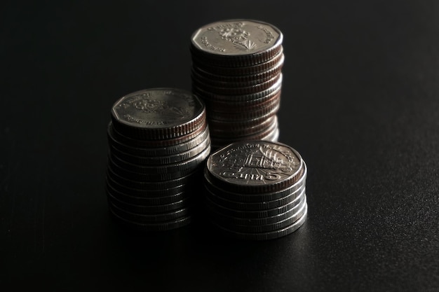 Foto pilha de moedas de dinheiro em fundo preto, economizando o conceito de dinheiro