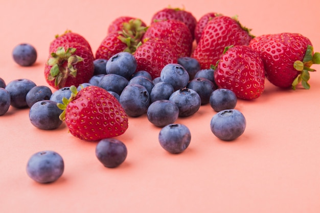 Pilha de muitas frutas maduras frescas isoladas em fundo laranja