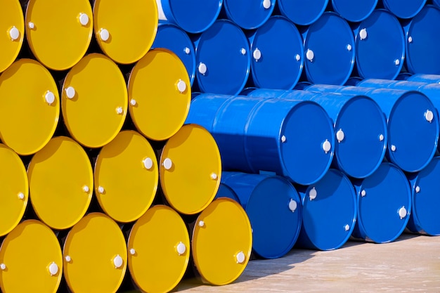 Pilha de muitos tambores de óleo amarelos e azuis de 200 litros no chão na área do pátio industrial
