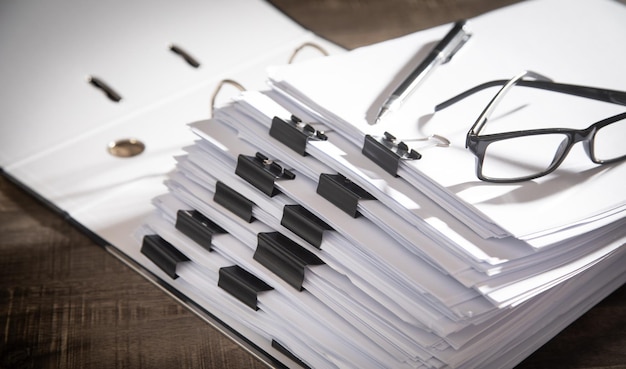 Pilha de óculos de documentos e caneta na mesa no escritório