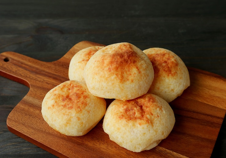 Foto pilha de pães de queijo brasileiros caseiros ou pao de queijo em uma tábua de madeira