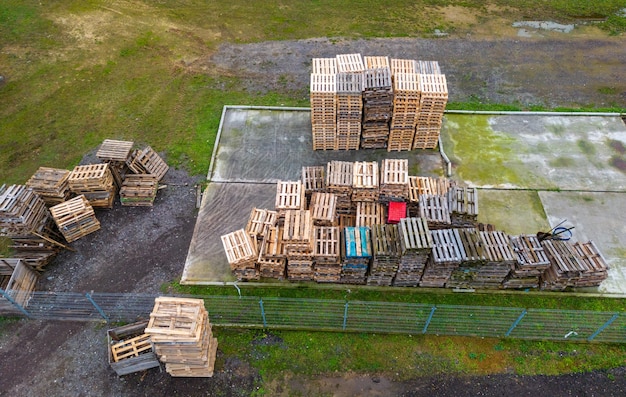 Pilha de paletes de madeira vista aérea Área de armazenamento de paletes ao ar livre sob o telhado ao lado da granja Pilhas de paletes de carga Eurotype em uma instalação de reciclagem de resíduos