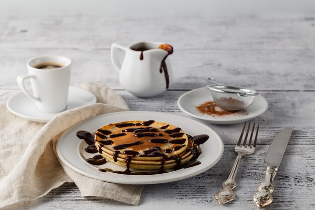 Pilha de panquecas com calda de banana e chocolate