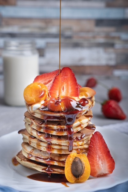 Pilha de panquecas com calda de morango, damasco e caramelo