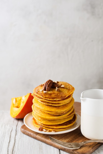 Pilha de panquecas com noz-pecã e calda em estilo nórdico em fundo branco