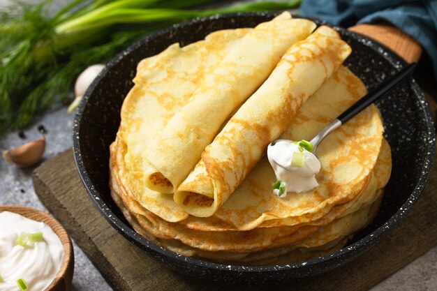 Pilha de panquecas de batata não doces servidas com molho de creme de alho em um fundo de pedra cinza