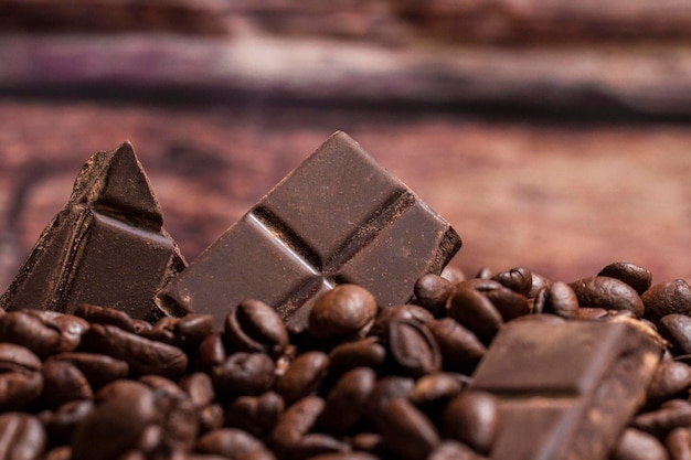 Pilha de pedaços de chocolate com grãos de café em um fundo de madeira horizontal com espaço de cópia