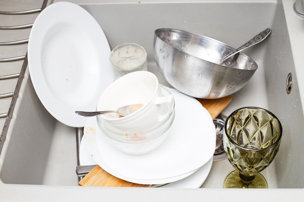 Pilha de pratos sujos como talheres de pratos na pia de granito cinza moderno na cozinha