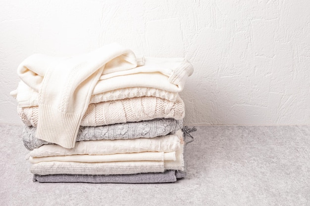 Pilha de roupas de malha brancas aconchegantes para clima frio. Suéteres orgânicos de conforto. Ideia de estilo hygge