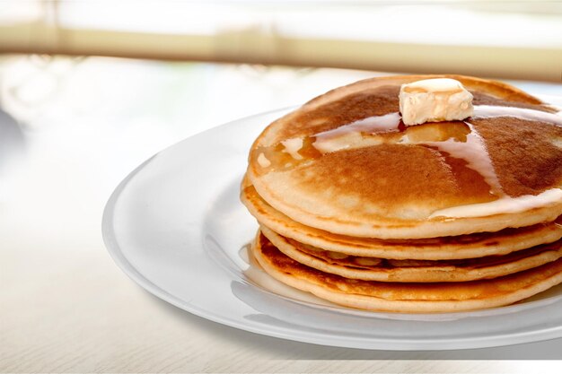 Pilha de saborosas panquecas com manteiga em um prato branco