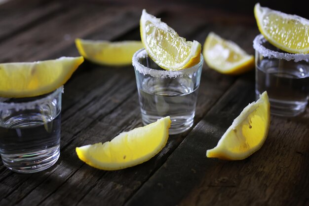 Pilha de tequila com sal e limão em um fundo de madeira