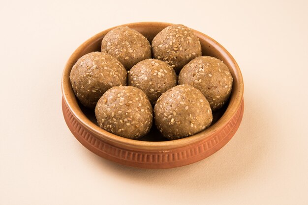 Foto pilha de tilgul laddu ou til gul laddoo feita à mão feita de açúcar mascavo ou gud e sementes de gergelim para o festival makar sankranti, servida em uma tigela. foco selecionado