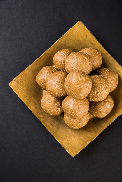 Pilha de Tilgul Laddu ou Til Gul Laddoo feita à mão feita de açúcar mascavo ou gud e sementes de gergelim para o festival Makar Sankranti, servida em uma tigela. foco selecionado