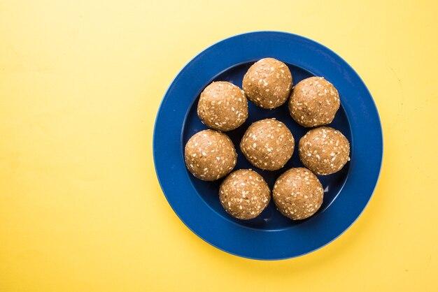 Pilha de Tilgul Laddu ou Til Gul Laddoo feita à mão feita de açúcar mascavo ou gud e sementes de gergelim para o festival Makar Sankranti, servida em uma tigela. foco selecionado