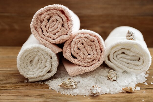 Pilha de toalhas de banho na mesa de madeira. Toalhas felpudas brancas e rosa de algodão. Conceito de spa. Foto tonificada.