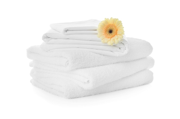 Pilha de toalhas e lençóis com gerbera em fundo branco