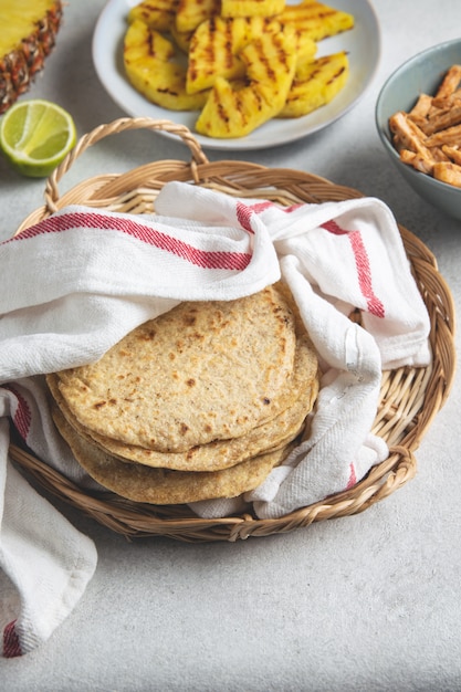 Pilha de tortilhas de milho mexicano em uma bandeja de vime coberto com toalha de cozinha