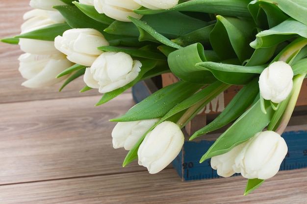 Pilha de tulipas brancas frescas em um fundo de madeira