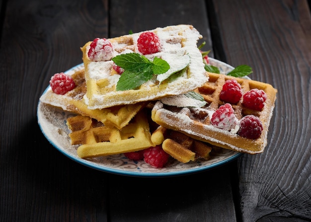 Pilha de waffles belgas assados com framboesa vermelha madura polvilhada com açúcar em pó