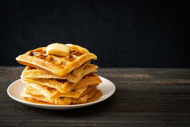 Pilha de waffles caseiros com manteiga e mel ou xarope de bordo