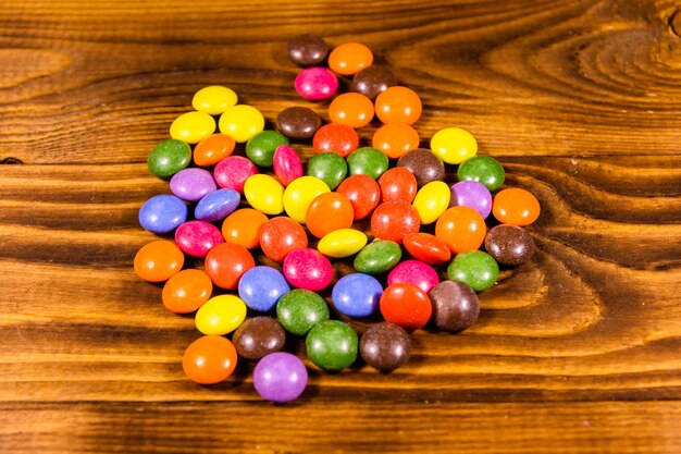 Pilha dos doces multicoloridos em uma mesa de madeira