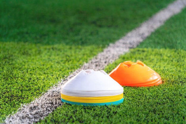 Pilhas de cone de marcador de esporte no campo de treinamento com a linha de fronteira branca.