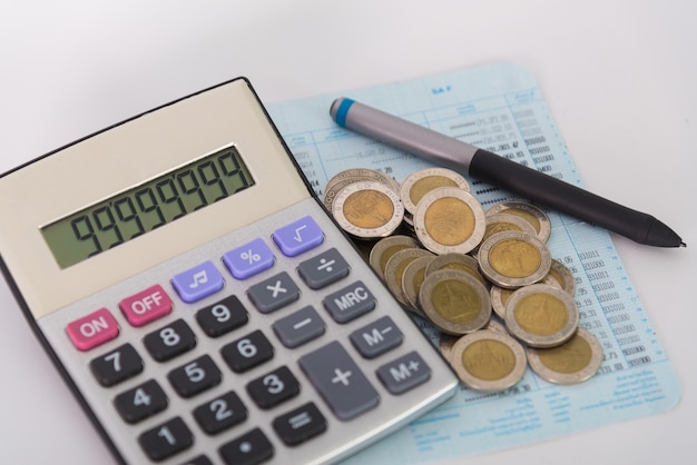 Pilhas de moedas e calculadora com caneta