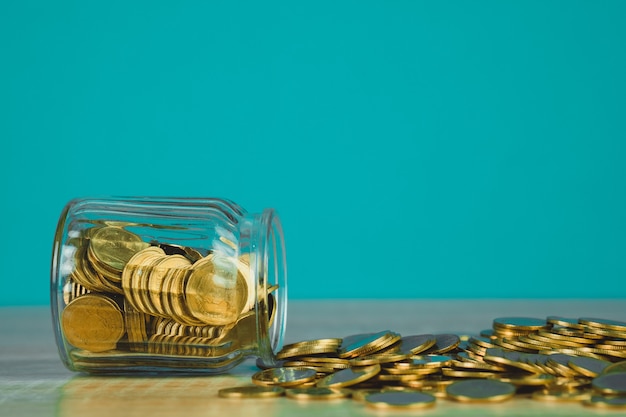 Pilhas de moedas e dinheiro de moedas de ouro no pote de vidro na mesa