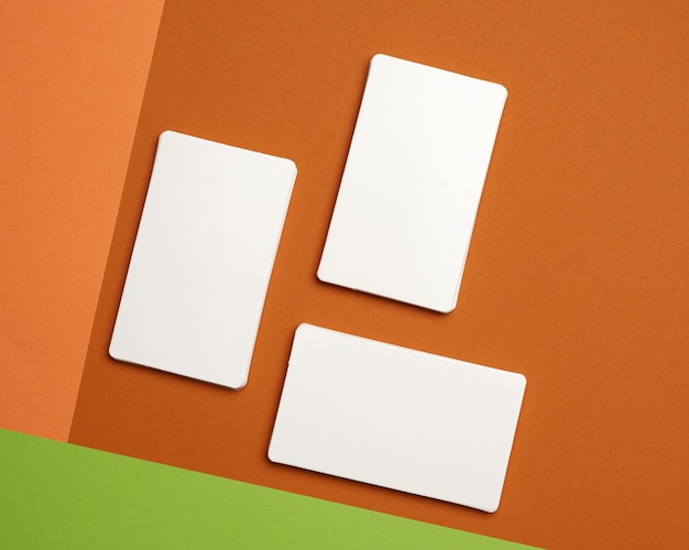 Pilhas de papel branco cartões de visita em branco sobre fundo verde-alaranjado