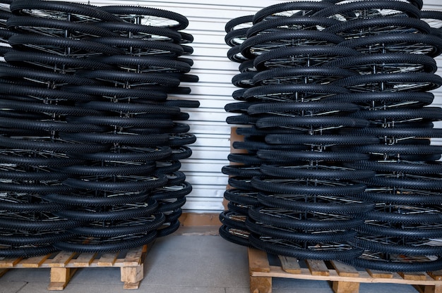 Pilhas de rodas de bicicleta novas em um palete, ninguém. loja de peças de bicicleta na fábrica, pneus no hangar, fileiras de aros e pneus para bicicletas