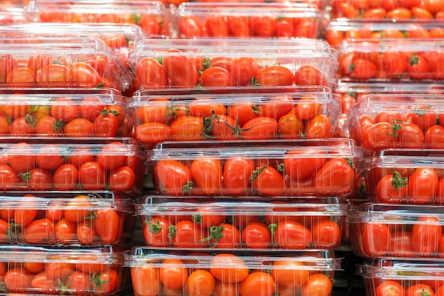 Pilhas de tomate cereja vermelho em recipientes de plástico fechados em um supermercado