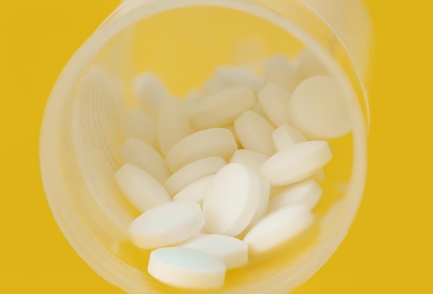 Pillen in einem Plastikbehälter auf einem gelben Hintergrund Nahaufnahme Makroaufnahme