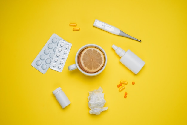 Pillen, medizinisches Thermometer, Nasenspray und Zitronentee