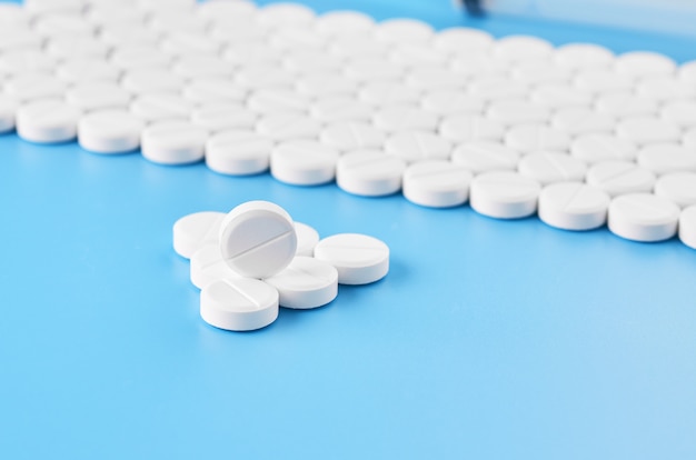 Pillen Tabletten Kapseln Nahaufnahme. Auf einem blauen Hintergrund ein Glas Medizin.