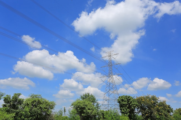 Pilón de la electricidad de líneas eléctricas de alto voltaje en campo verde con las nubes hermosas en el cielo azul.