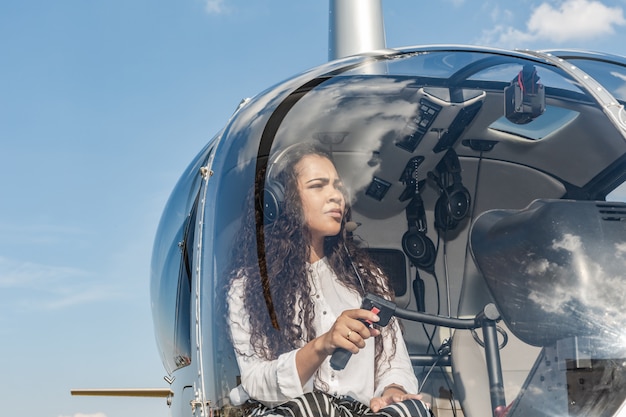 Pilotin im Cockpit des Hubschraubers vor dem Start. Junge Frau Hubschrauberpilot.