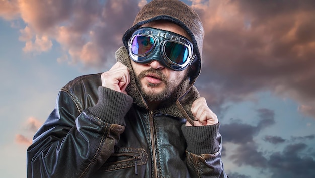 piloto de los años 20 con gafas de sol y casco de aviador vintage. Viste chaqueta de cuero, barba y rostros expresivos.