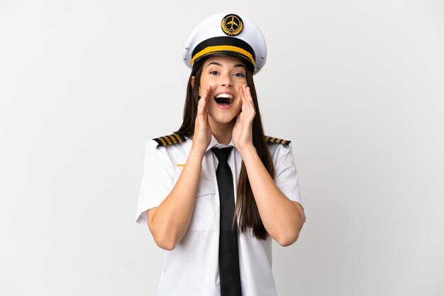 Piloto de avión chica brasileña sobre fondo blanco aislado gritando y anunciando algo