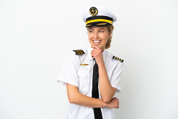 Piloto de avión mujer rubia aislado sobre fondo blanco mirando hacia el lado y sonriendo