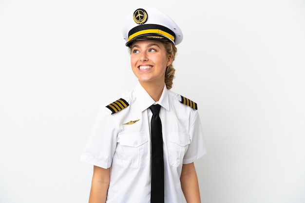 Piloto de avión mujer rubia aislado sobre fondo blanco pensando en una idea mientras mira hacia arriba