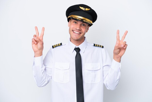 Piloto caucasiano de avião isolado no fundo branco, mostrando sinal de vitória com as duas mãos