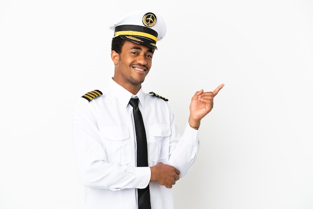 Piloto de avião afro-americano sobre fundo branco isolado apontando o dedo para o lado