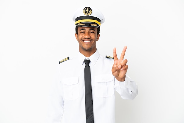 Piloto de avião afro-americano sobre fundo branco isolado sorrindo e mostrando sinal de vitória